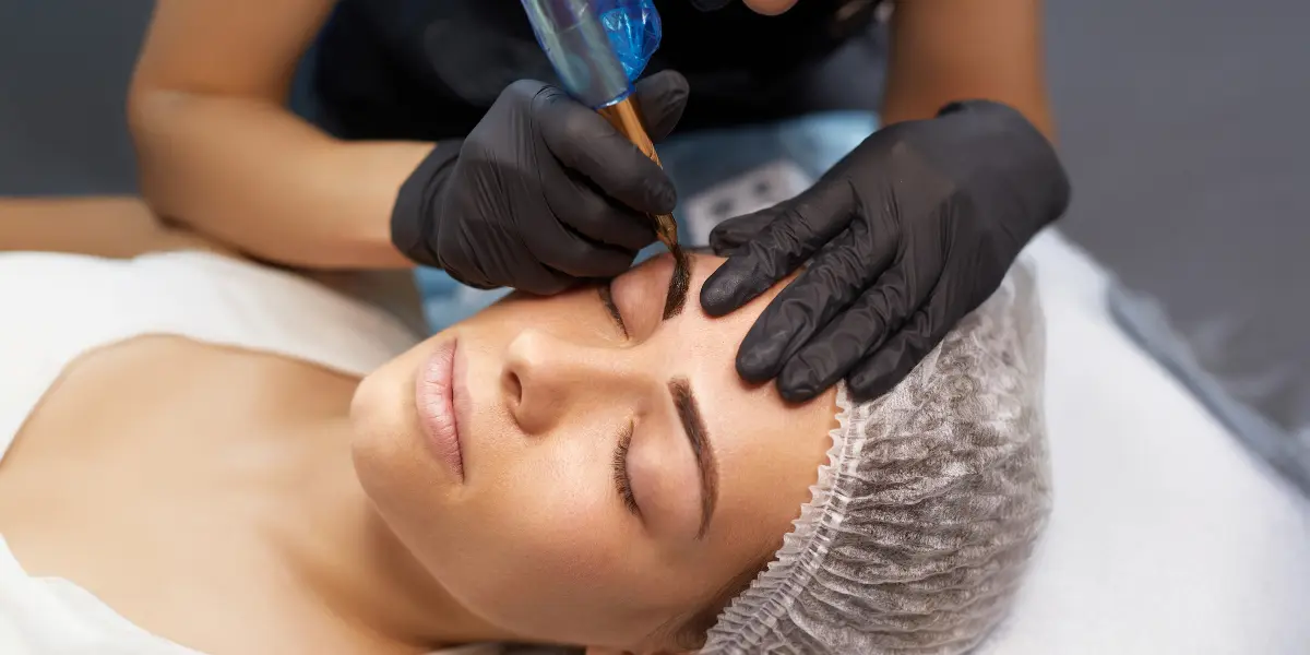 Especialista realizando microblading de cejas con blade manual sobre clienta